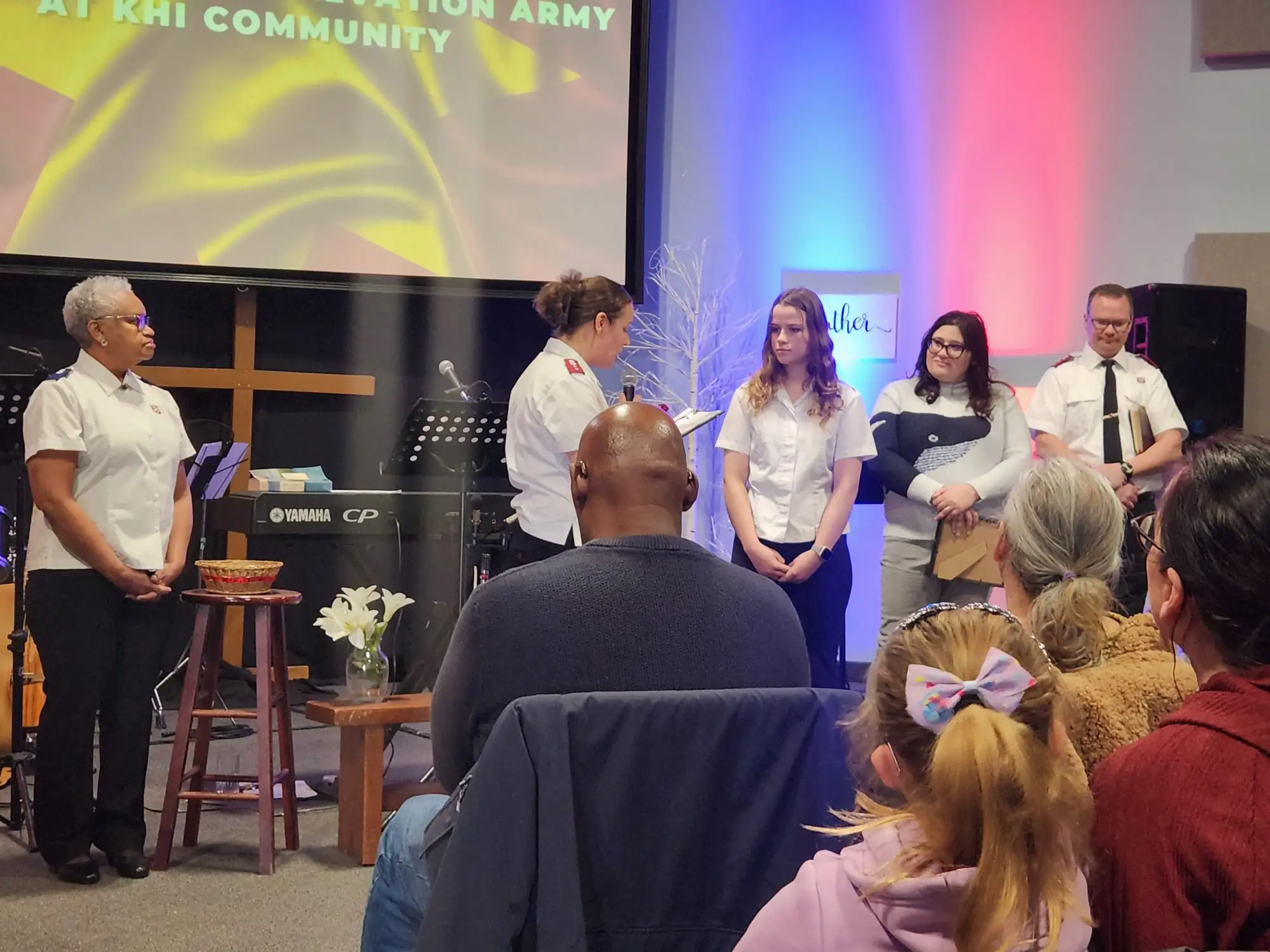 Three Salvation Army soldiers stand to present two individuals with soldiership or adherent status
