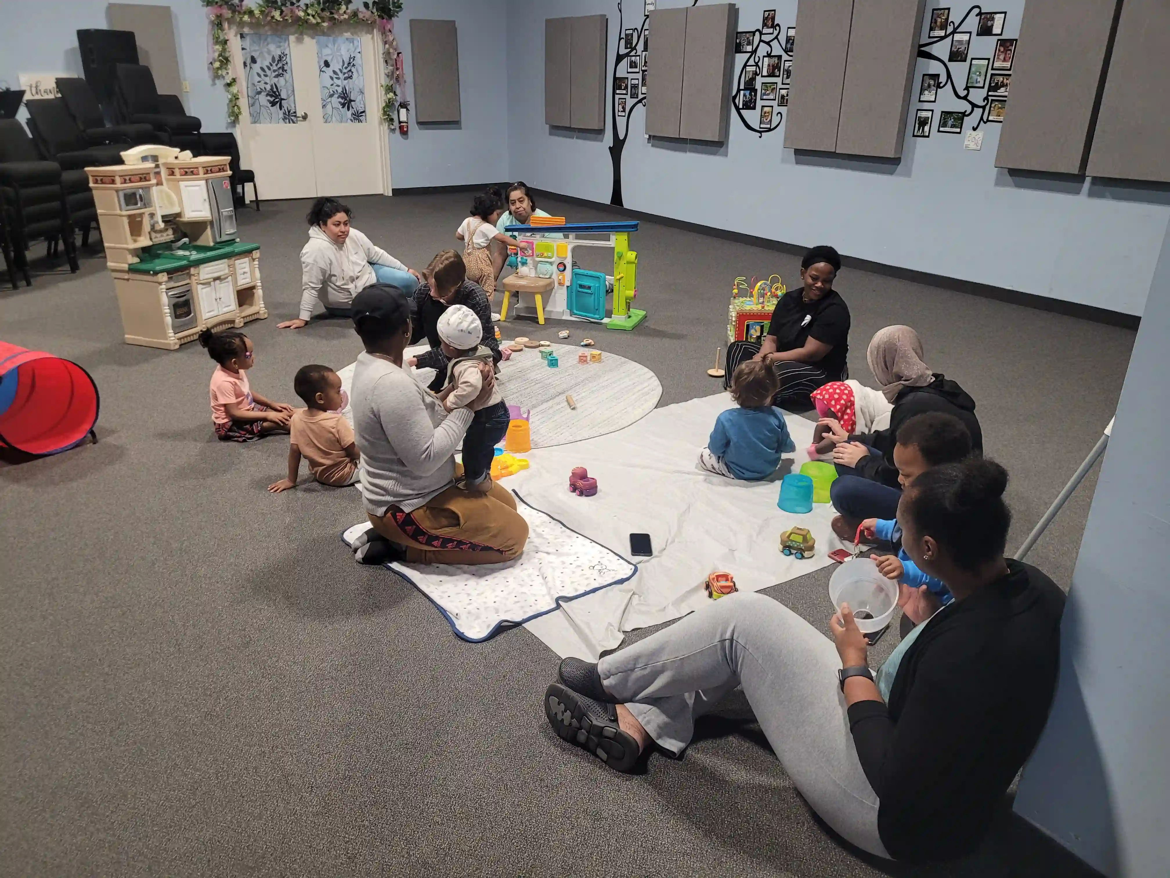 A group of parents and children play with toys on a the floor