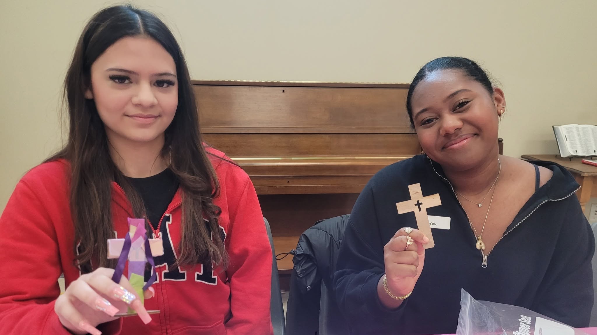 Two teenagers hold handheld crosses which they have decorated