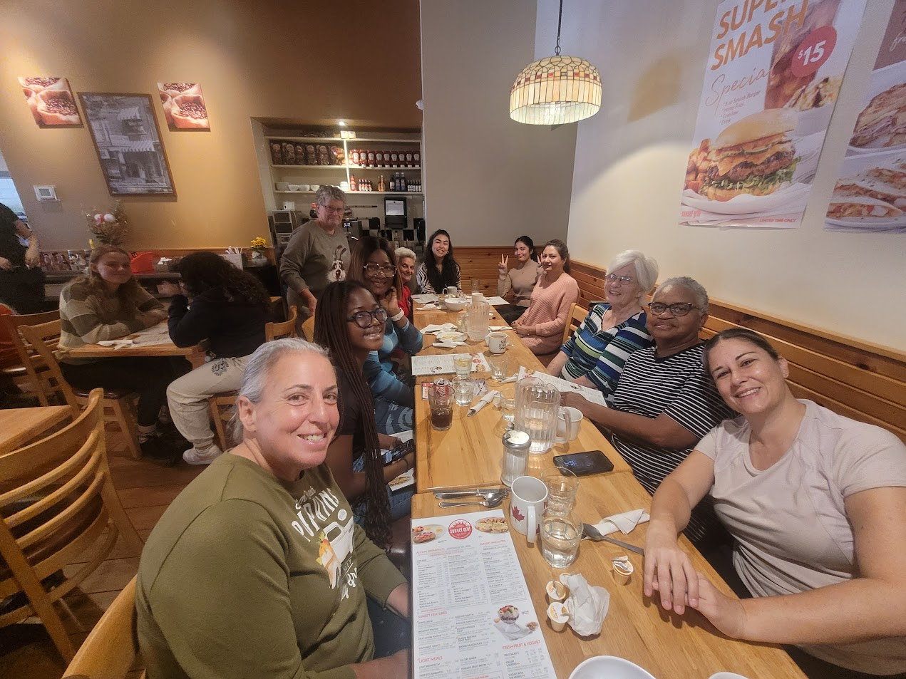 Thirteen women sit at two tables over breakfast