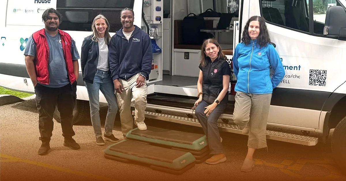Five people gather in front of the mobile health clinic van outside The Salvation Army Milton